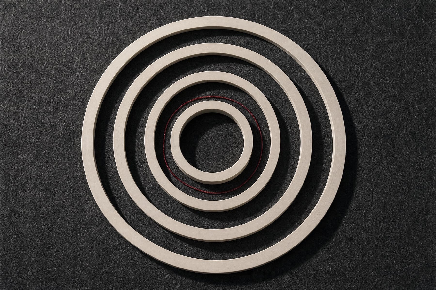 Bone sizing rings of increasing diameter laid out flat, one singled out with a wine thread